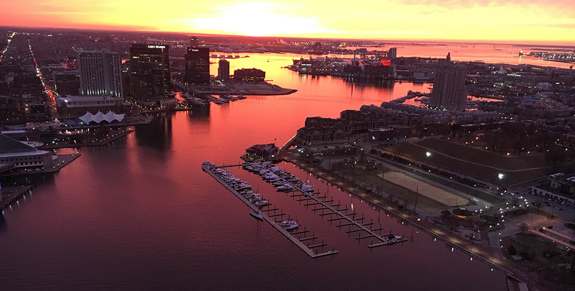 The river winding through downtown Baltimore reflects orange in the sunset.